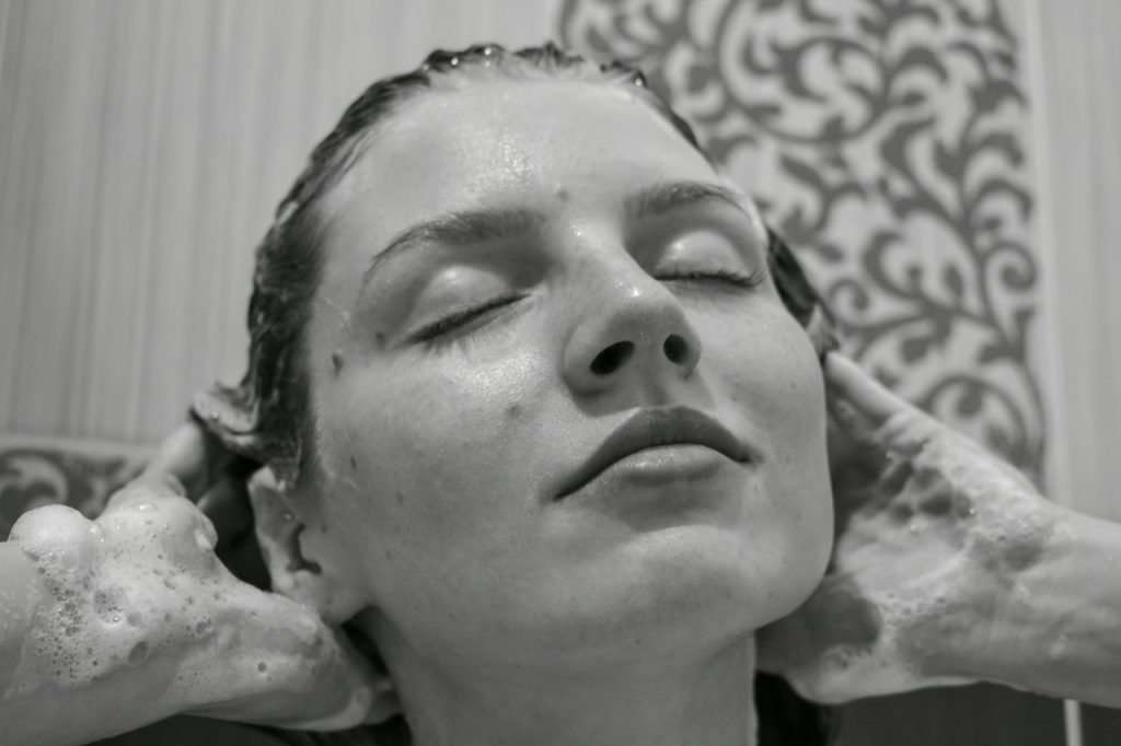 Mujer lavándose la cabeza con un champú sólido natural.